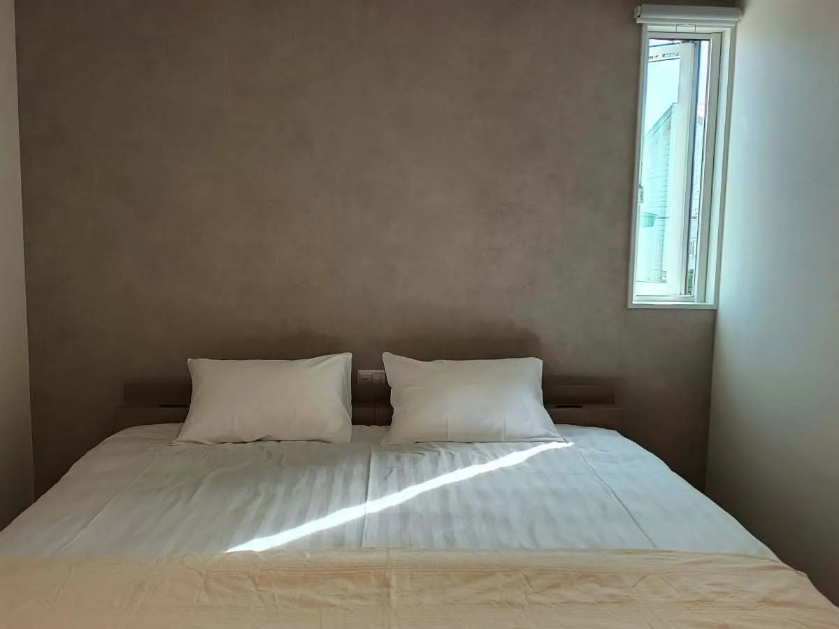 Double bed against a textured plaster wall