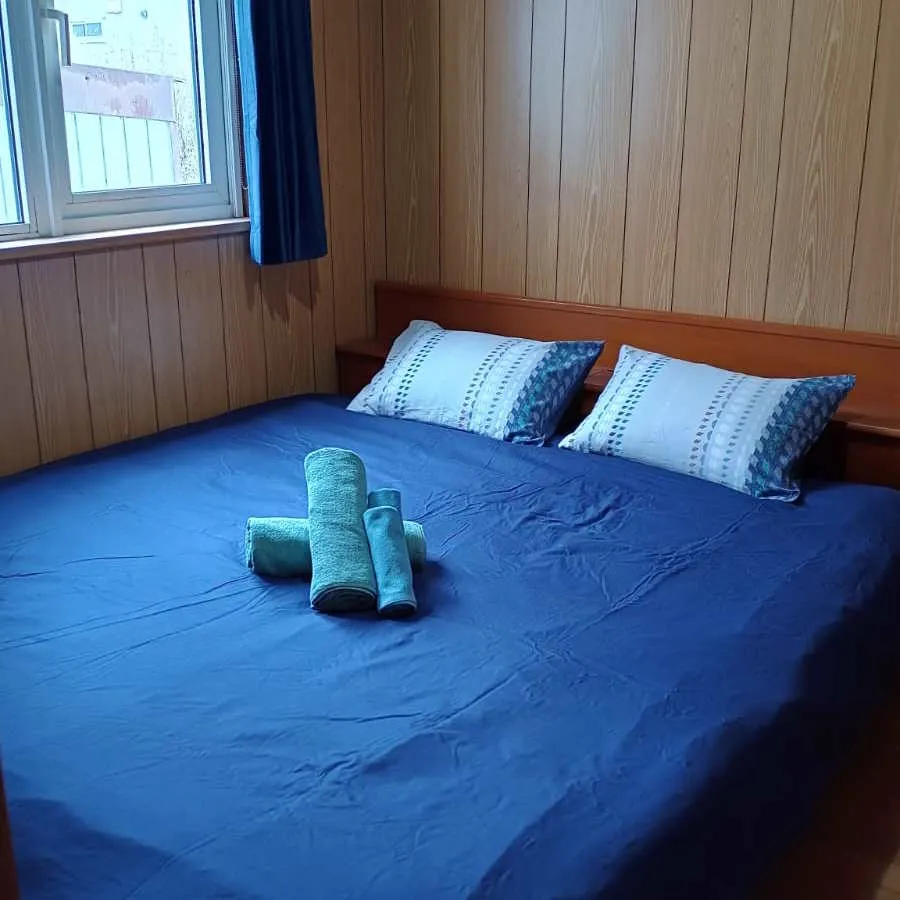 Double bed with blue duvet and towels on wood panelling