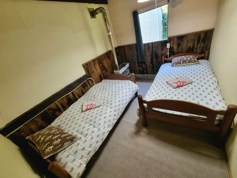 Bedroom with two single beds, wood-panelled walls and garden view