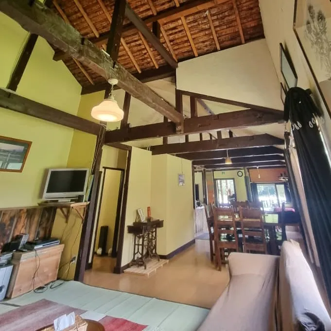 Living and dining area with exposed wooden beams and high ceiling